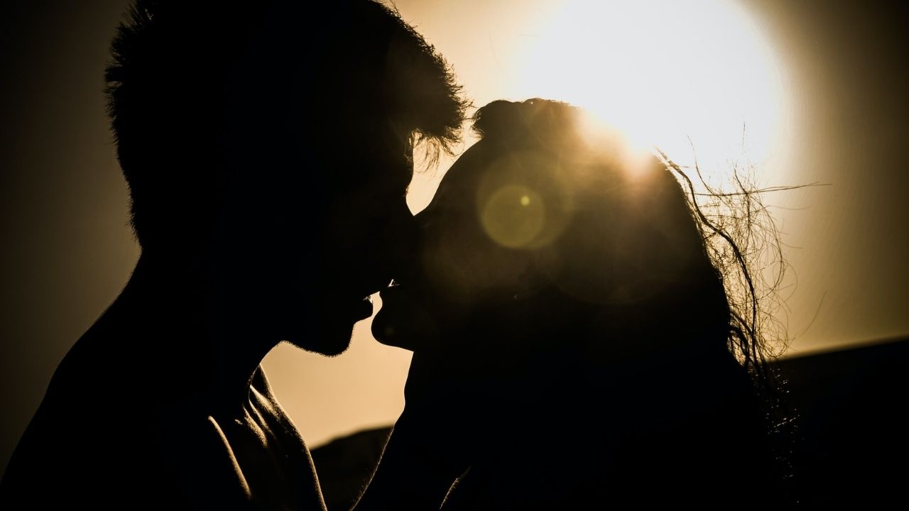 Man and women kissing under the sun