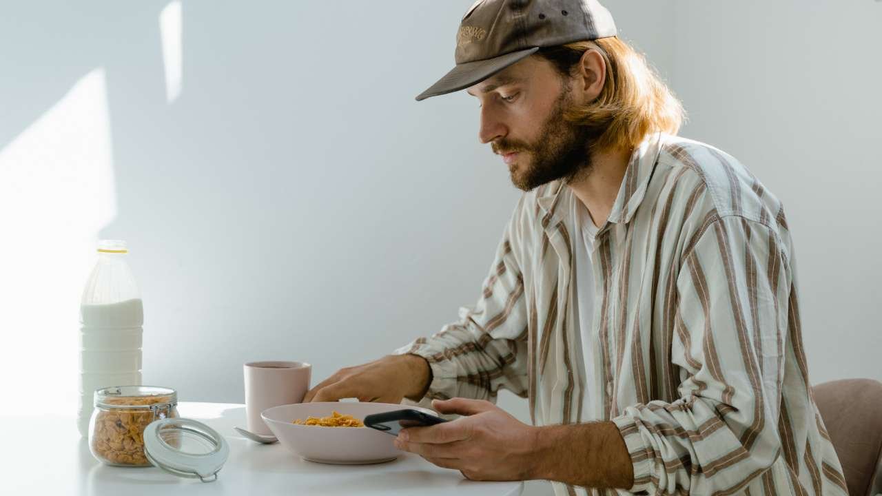 man eating breakfast while using phone
